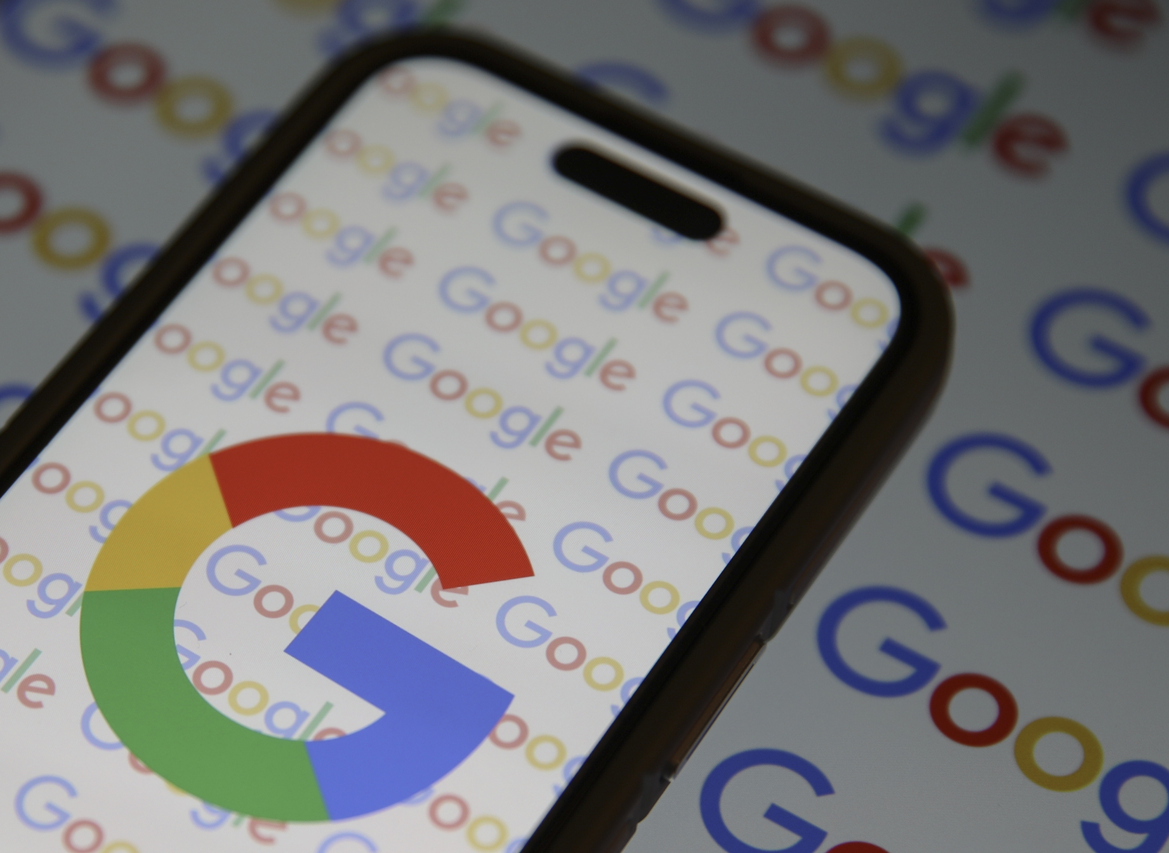 The Google logo prominently displayed on a smartphone and on paperwork beneath the smartphone.